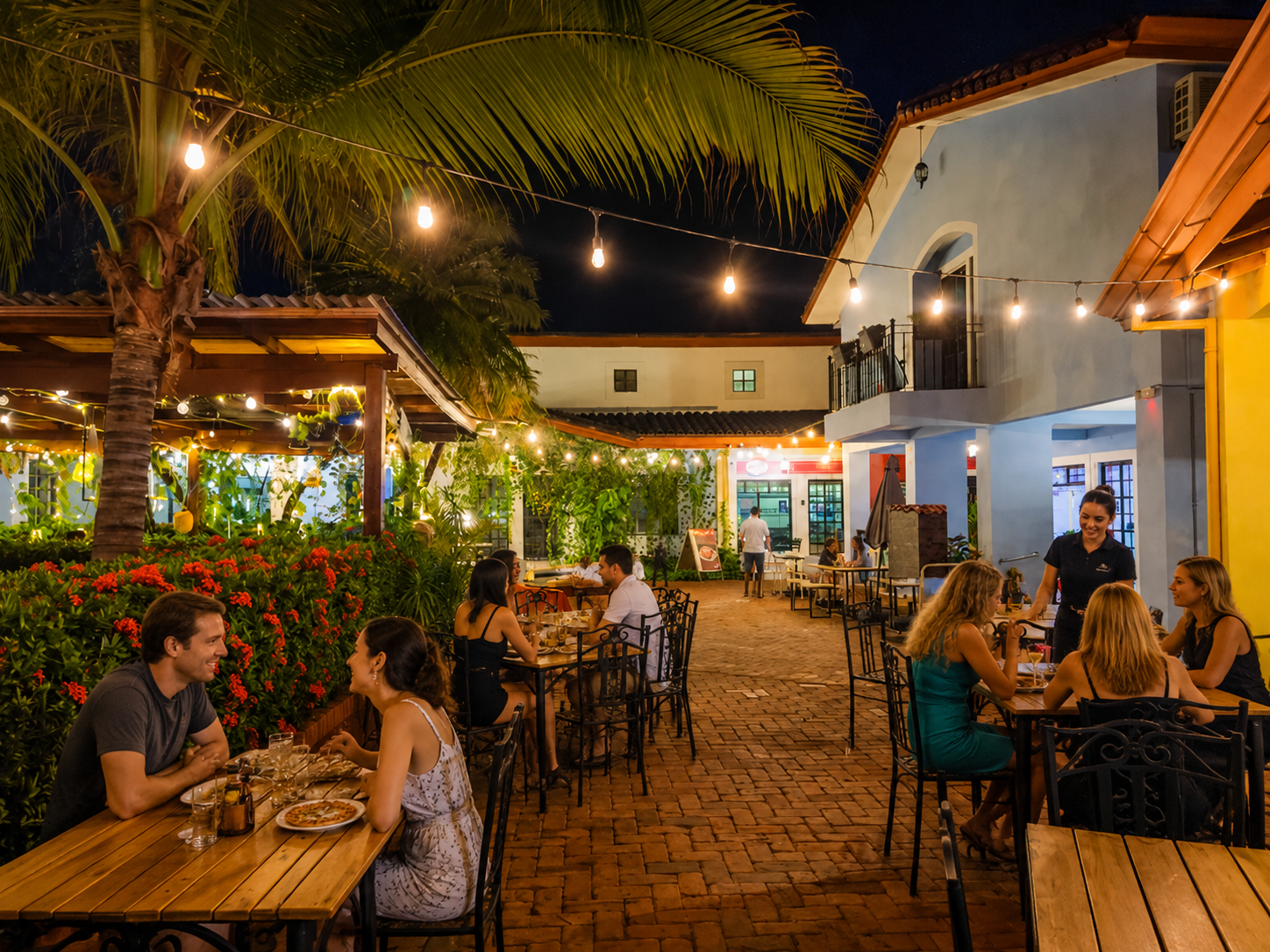 Outdoor restaurant patio at Pueblito Sur in the evening with string lights and palm trees